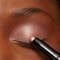 A woman applying a shimmery eye shadow to her eye lids.