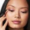 A photo of a woman using liquid eye liner to make winged tips