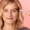 A person filling in their eyebrows with an eyebrow pencil
