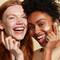 Side by side image of two women smiling applying IT Cosmetics face cream