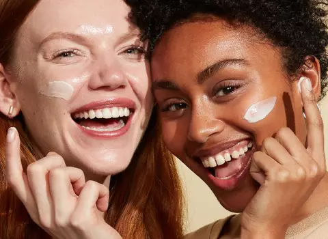Side by side image of two women smiling applying IT Cosmetics face cream