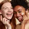 Side by side image of two women smiling applying IT Cosmetics face cream