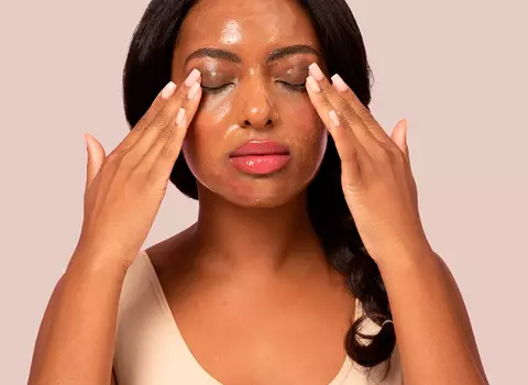 A person rubbing a cleaning balm into their face