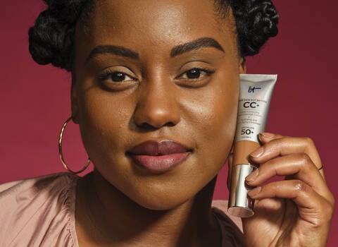 A photo of a woman smiling in a full face of makeup and red lipstick
