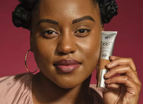 A photo of a woman smiling in a full face of makeup and red lipstick