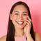 A person lightly touching their face, with a slight smile.
