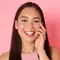 A person lightly touching their face, with a slight smile.