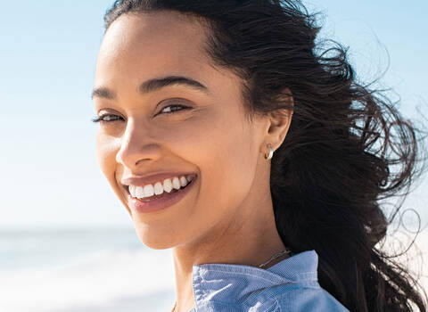 A photo of a smiling person standing on a beautiful beach.