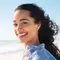 A photo of a smiling person standing on a beautiful beach.