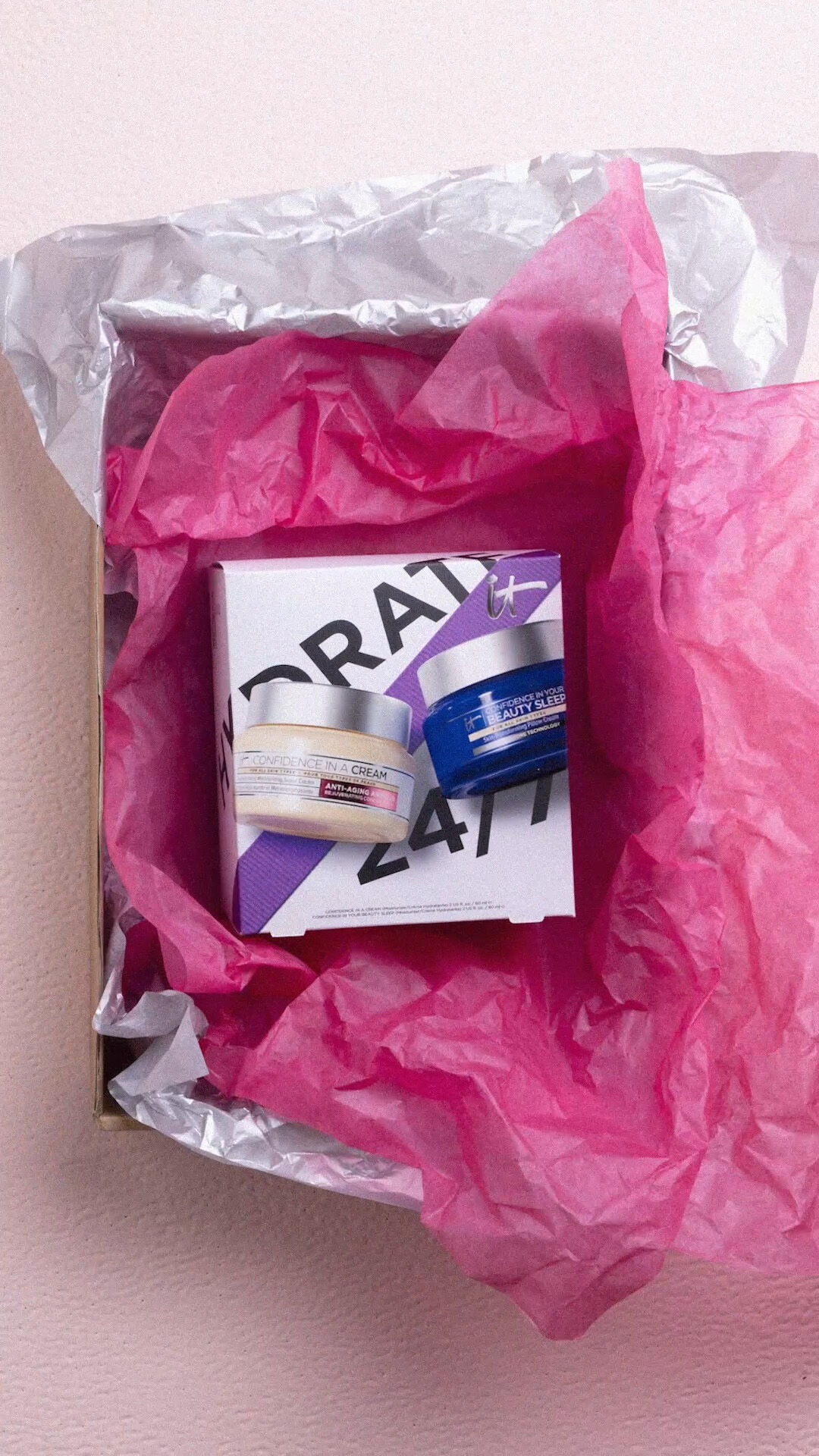 The IT Cosmetics Celebrate 24/7 Hydration Anti-Aging Skincare Set inside a larger box with pink and silver tissue paper.