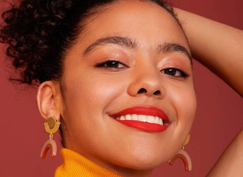 A model smiling wearing IT Cosmetics makeup