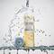 A bottle of IT Cosmetics Confidence In A Gel Lotion with the bottle cap next to it on a ledge being showered with water.