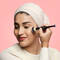 A model using a makeup brush to apply foundation