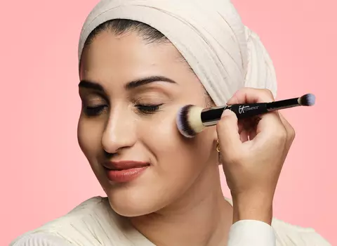 A model using a makeup brush to apply foundation