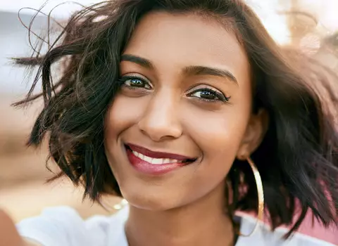 A photo of someone smiling with a lightweight foundation on their face.