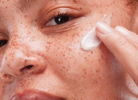 A woman applying a facial cream to her face