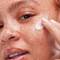 A woman applying a facial cream to her face