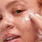A woman applying a facial cream to her face