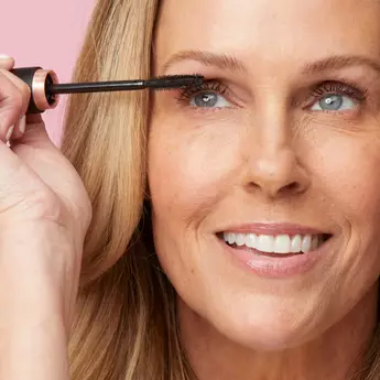 A closely cropped photo of a woman's face while she applies mascara.