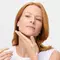 A photo of a woman putting a lotion on her neck