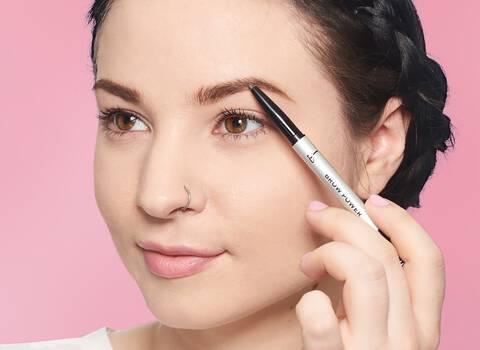 A photo of a woman using an eyebrow pencil