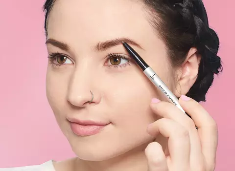 A photo of a woman using an eyebrow pencil