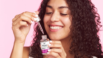 Woman with curly hair applying face serum