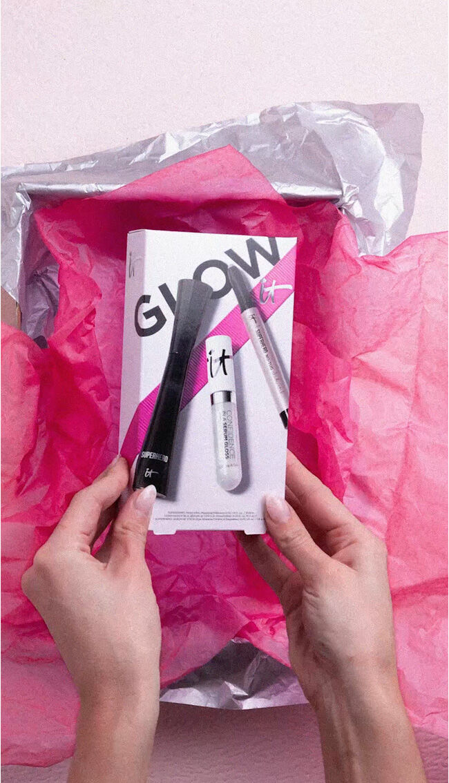 A photo of a pair of hands holding the IT Cosmetics Celebrate Effortless Glow Makeup Gift Set.