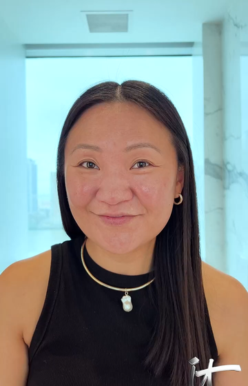 A picture of a woman with long dark brown hair, without makeup, looking at the camera.