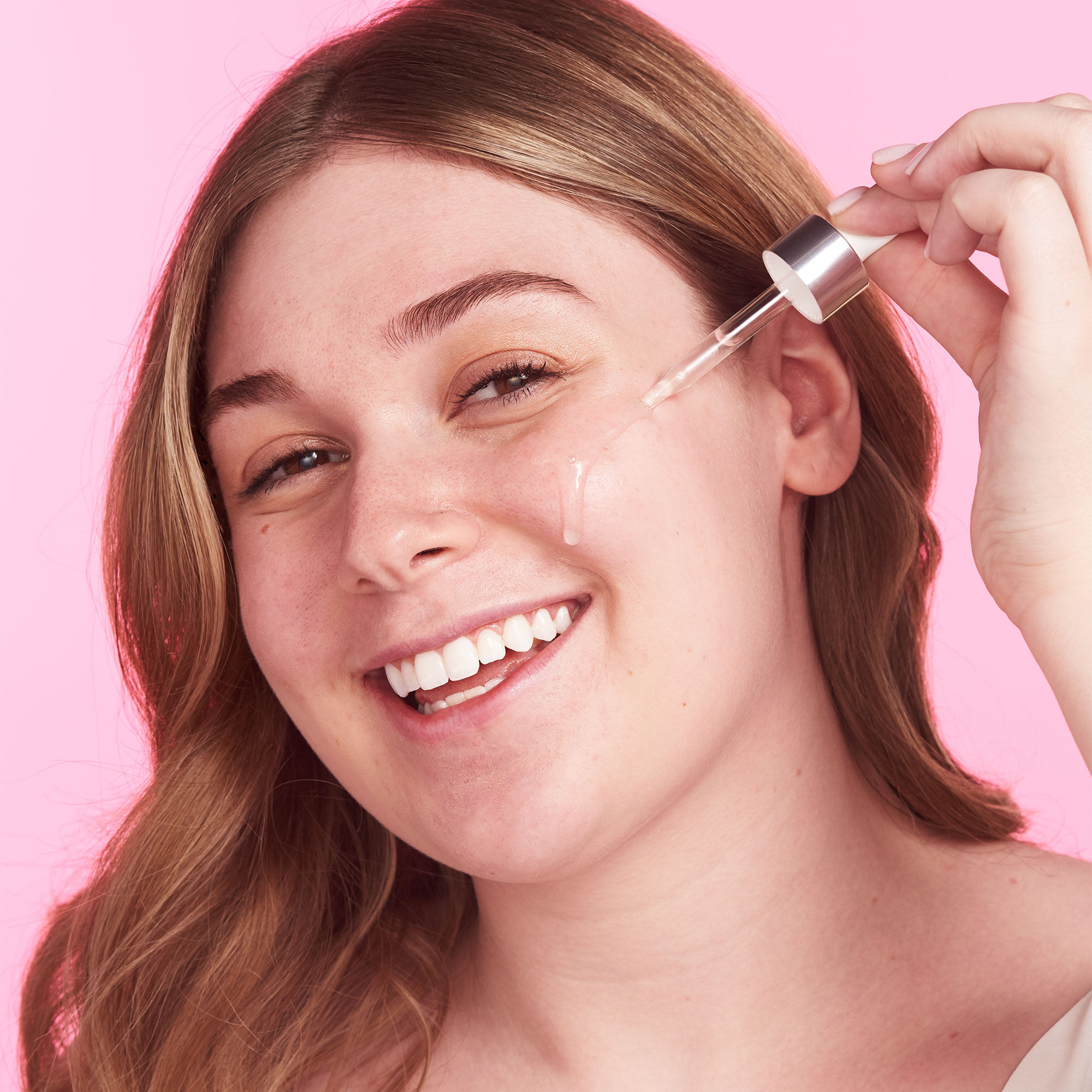 A woman putting a serum on her face