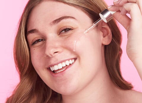 A woman putting a serum on her face