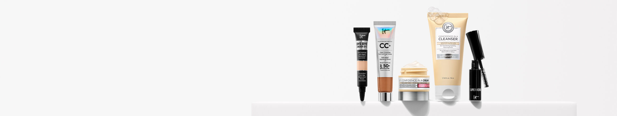 IT Cosmetics Bye Bye Under Eye Concealer and CC+ Full Coverage Foundation with SPF 50+ placed on a white ledge.