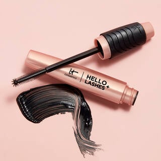 An open tube of IT Cosmetics Hello Lashes+ with the mascara brush resting on the tube next to a swipe of black mascara.