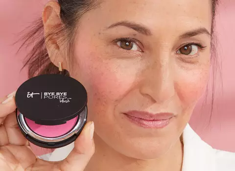 Woman with faint smile and dark hair holding up Bye Bye Pores Blush
