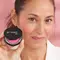 Woman with faint smile and dark hair holding up Bye Bye Pores Blush