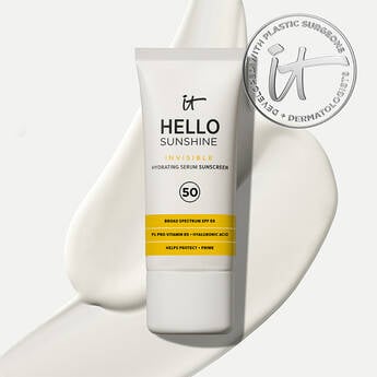 A photo of a bottle of IT Cosmetics Hello Sunshine Invisible Sunscreen For Face SPF 50 on a white background and a swipe of sunscreen, with an IT seal in the top right corner.