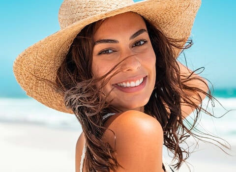A person in a big floppy straw hat on a beach