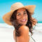 A person in a big floppy straw hat on a beach