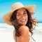 A person in a big floppy straw hat on a beach
