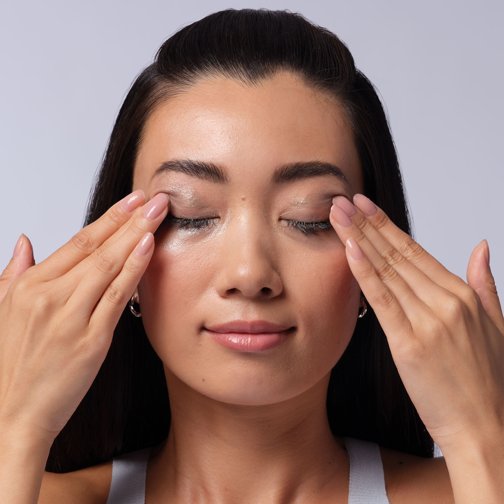 A woman using a cotton pad to remove makeup from her eyes