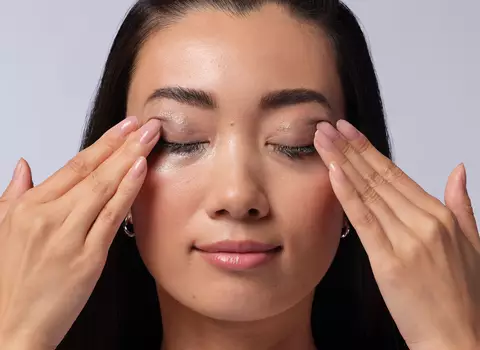 A woman using a cotton pad to remove makeup from her eyes
