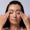 A woman using a cotton pad to remove makeup from her eyes