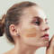 A photo of a woman with a light cream under her eyes