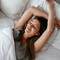 A photo of a woman smiling while laying in bed