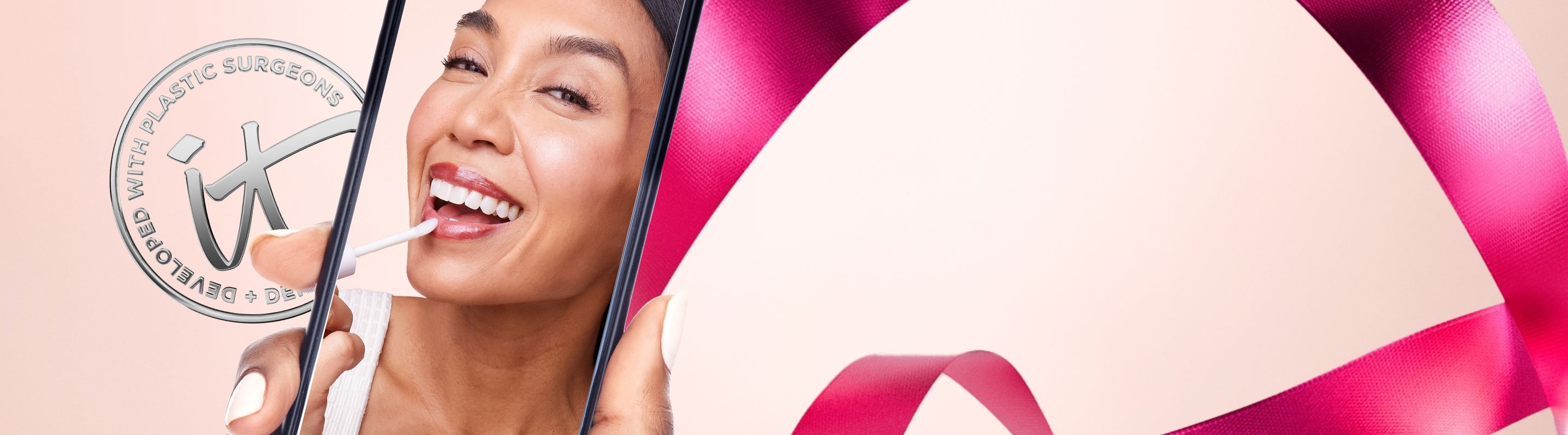 A banner that features a silver IT Cosmetics seal with the words "Developed with plastic surgeons," next to a photo of a woman taking a selfie with a phone and applying a lip product.